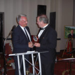 New Rebild President Jesper Jespersen presents the Rebild Plaque to retiring President Karl Nielsen. (Photo courtesy of The Danish Pioneer)