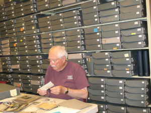 Peter L. Petersen, author of A Place Called Dana, written at the centennial of Dana College and Trinity Seminary, sorts some of the thousands of photos found in the DAAL collections. (Photo courtesy of DAAL)