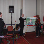 Ed Bladt and Birgit Jacobsen unveil the portrait for Karl Nielsen. (Photo courtesy of The Danish Pioneer)